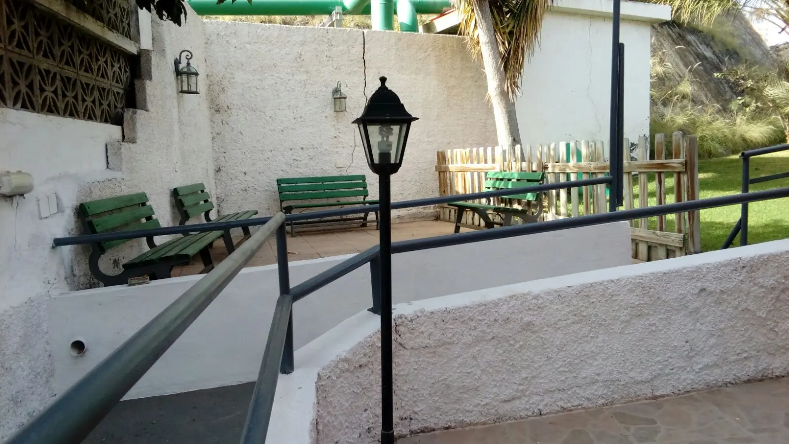 Rampa con pasamanos y bancos de descanso en el patio exterior del centro