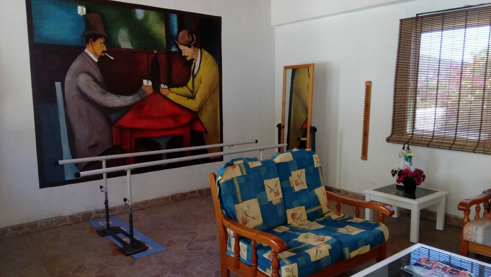 Sala de rehabilitación con paralelas de marcha y zona de descanso