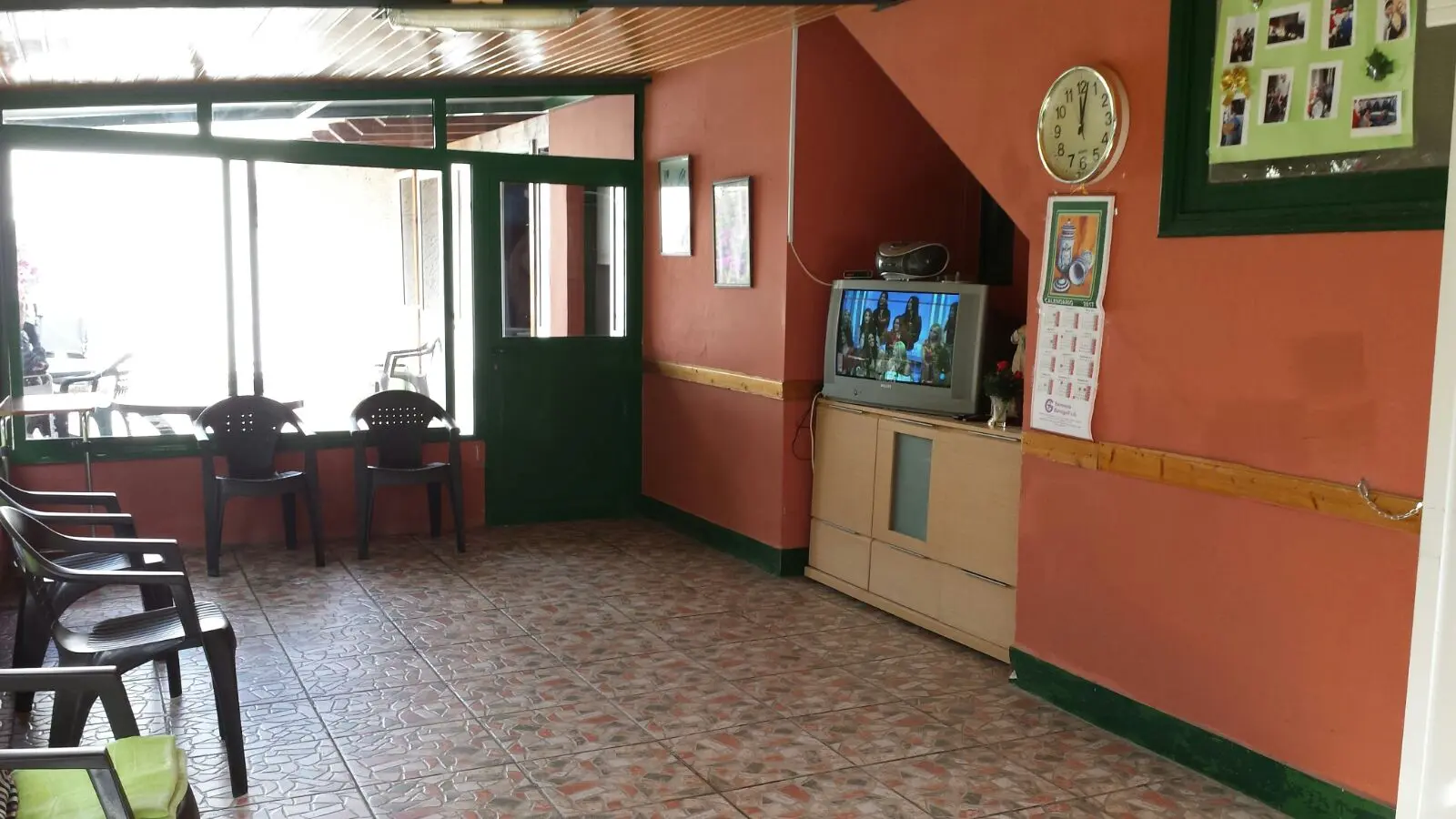 Terraza con sombrilla, mesas y bancos junto al acceso acristalado al interior