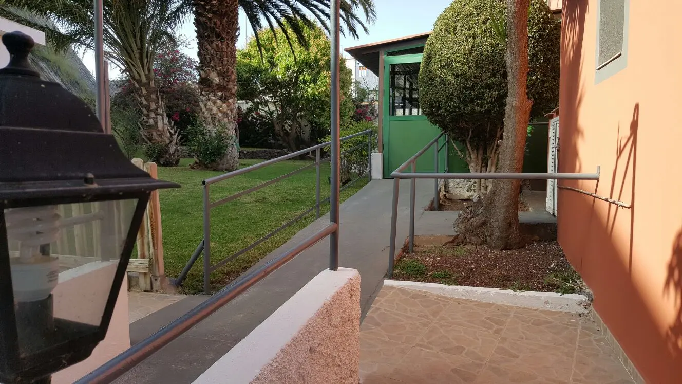 Camino accesible con pasamanos que cruza el jardín hasta la entrada del centro